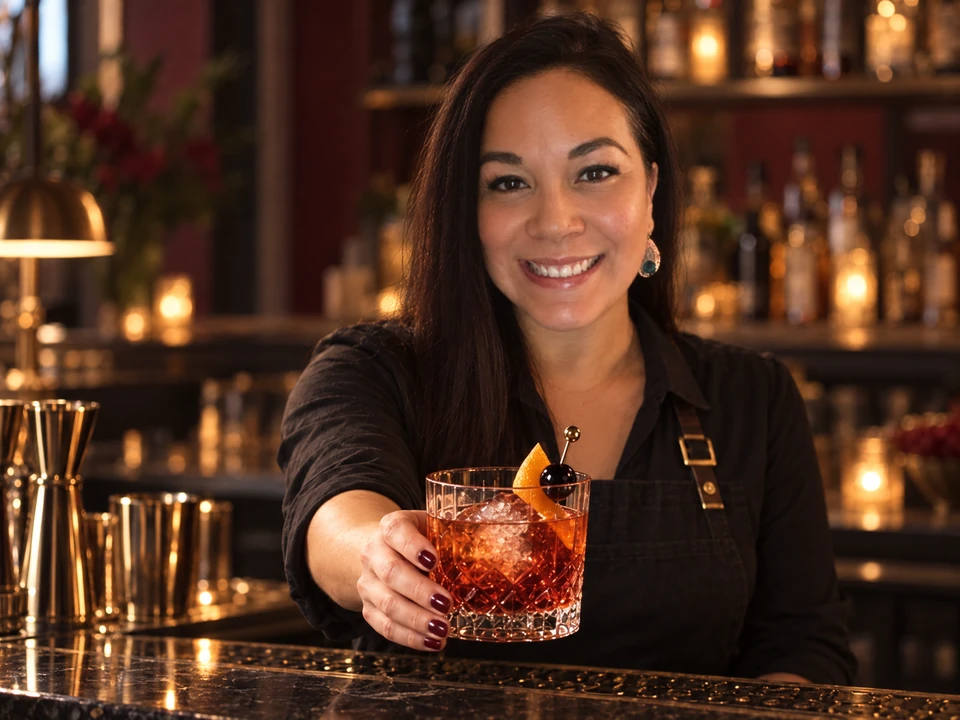Portrait of Crystal Bosquez offering a cocktail in a cut-crystal glass